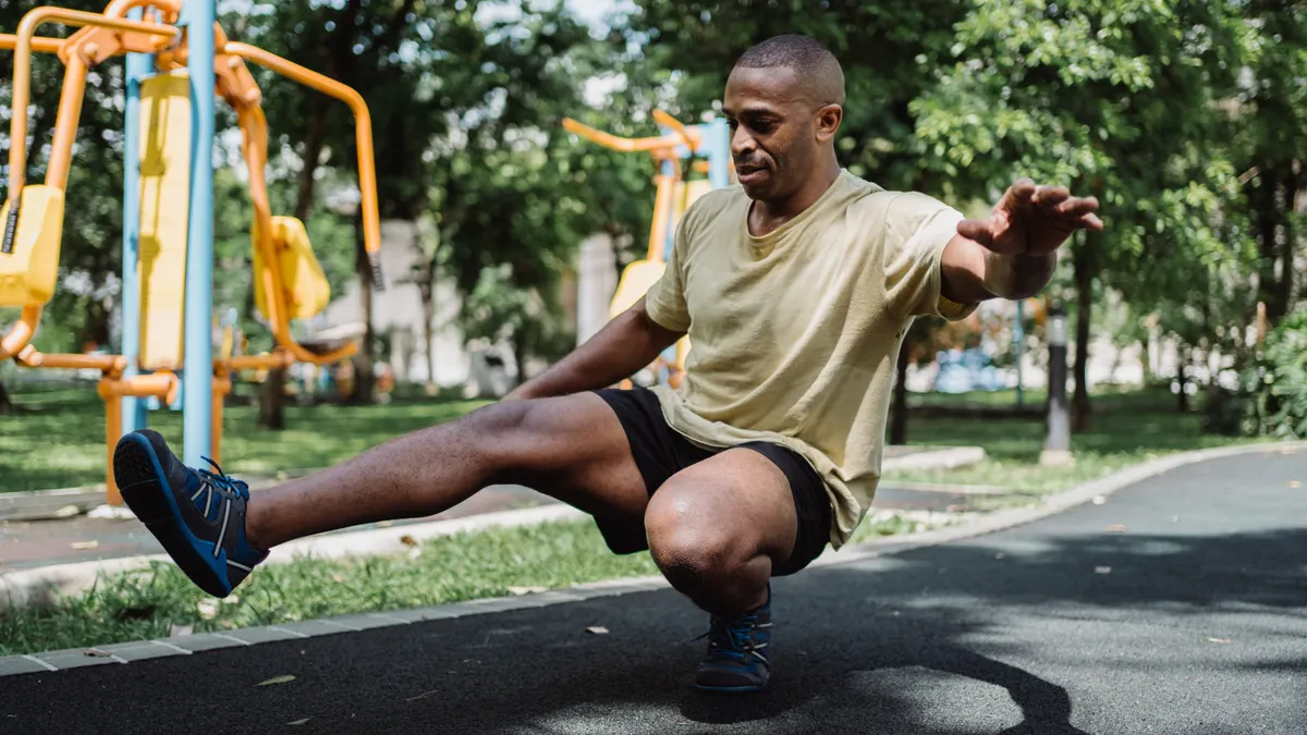 Coureur en équilibre sur une seule jambe dans un parc, un exercice de proprioception pour renforcer la cheville
