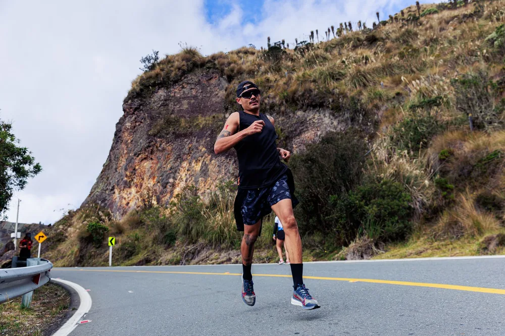 Coureur en pleine montée sur une route de montagne, mollets et tendon d'Achille fortement sollicités en côte