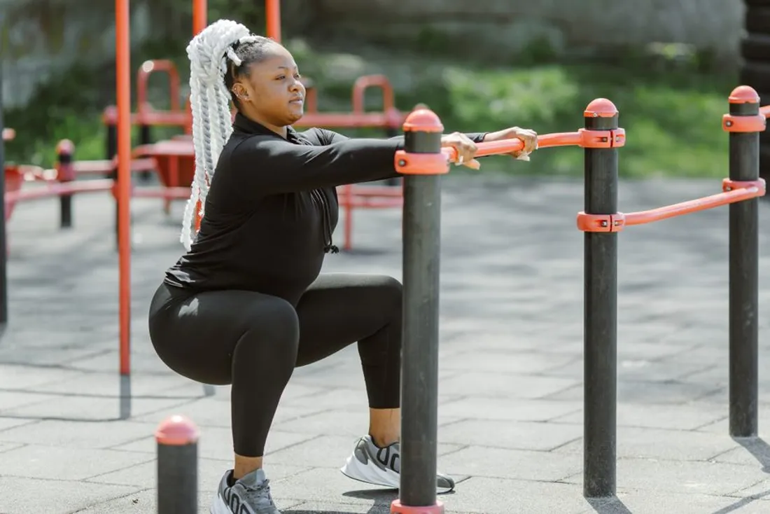 Femme réalisant un squat avec barre chargée en salle, exercice de base pour renforcer les quadriceps du coureur